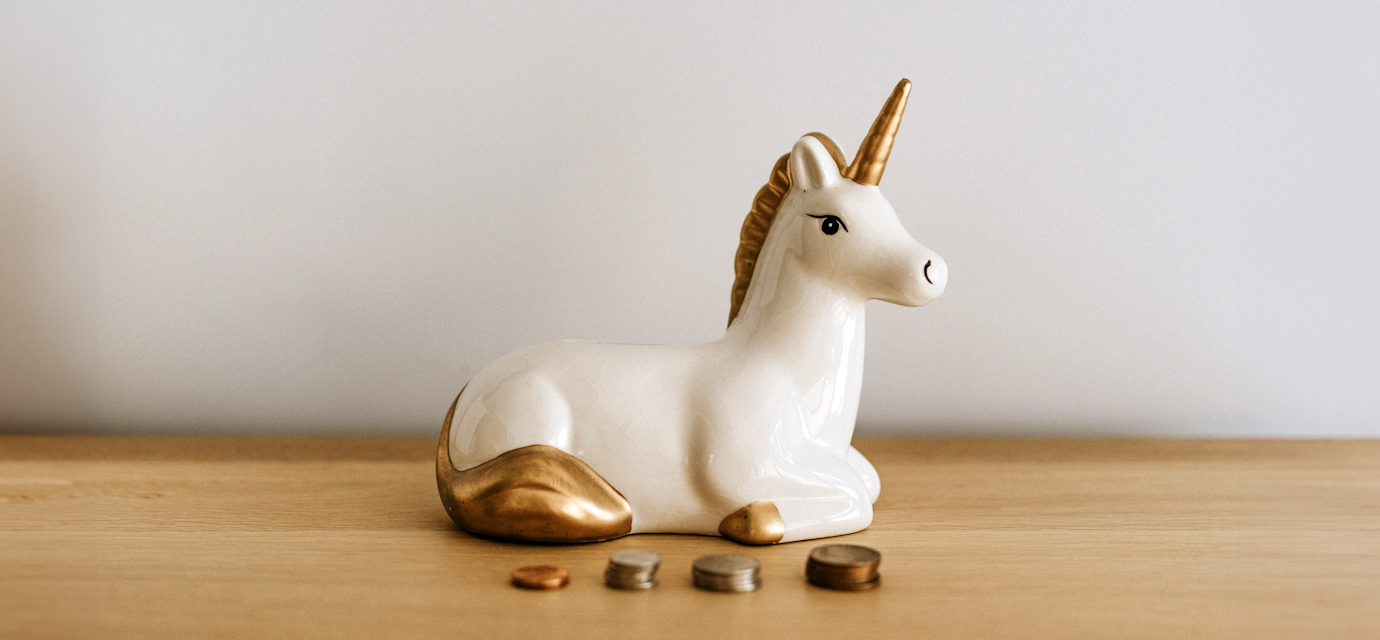 unicorn moneybox with piles of coins